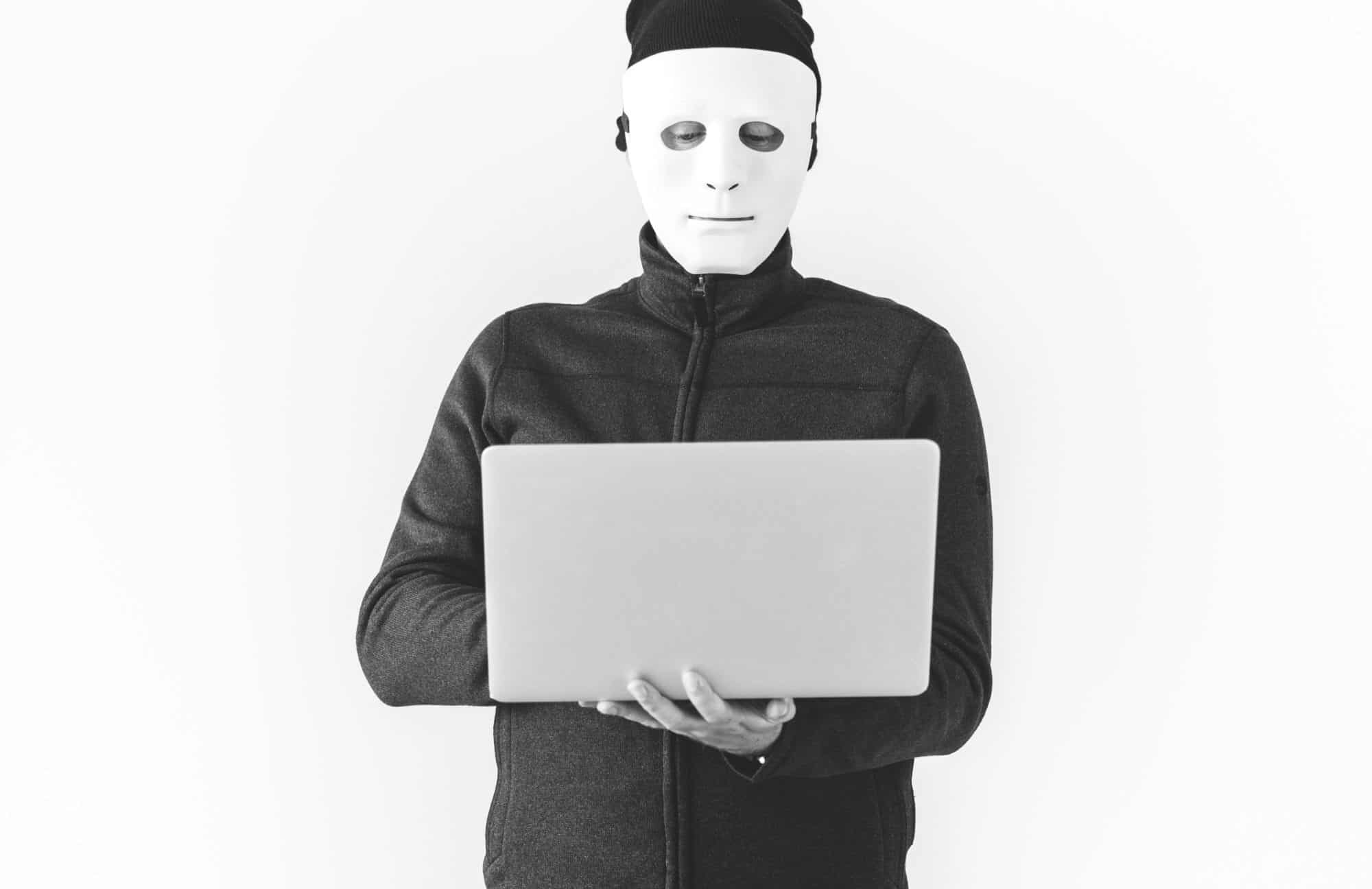 Man in mask holding laptop